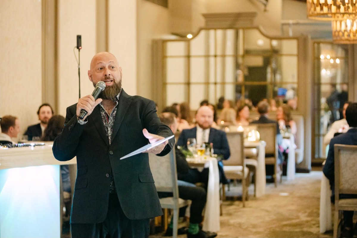 Joe Seyler speaking into a microphone at an event